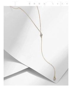 Detail of a minimalist gold Y-shaped necklace featuring sparkling bezel-set zircons