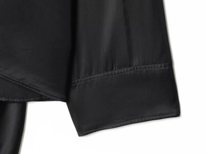 Detail shot of the black satin cloak sleeve showing fine stitching and silky texture