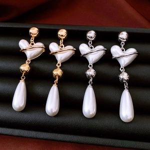 Detail view of vintage heart pearl drop earrings in gold and silver finish