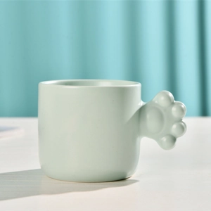 Detailed view of mint green ceramic mug featuring a unique 3D cat paw shaped handle