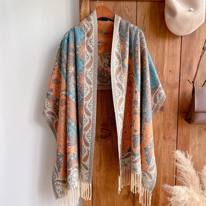 Ethnic bohemian shawl with paisley print and fringe hanging on a rustic wooden door