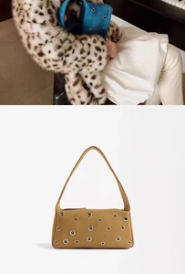 Close-up of stylish shoulder bag with metallic eyelets and smooth leather texture