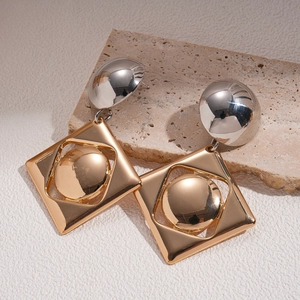 Detail of geometric silver ball earrings with gold hollow square frame and golden sphere