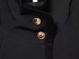 Macro detail of golden pebble-shaped textured buttons on a black blazer jacket