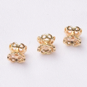 Macro detail of three gold hollow floral bead spacers for DIY jewelry making