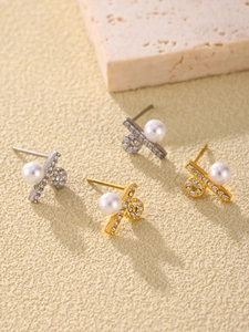 Close-up of gold and silver cross earrings with white pearls and sparkling cubic zirconia