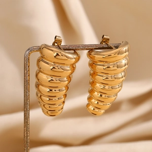 Close-up of golden spiral cicada chrysalis earrings on elegant light satin backdrop