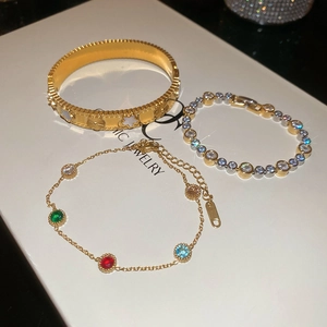 Detail of gold floral bangle and gemstone bracelets on a white jewelry display box