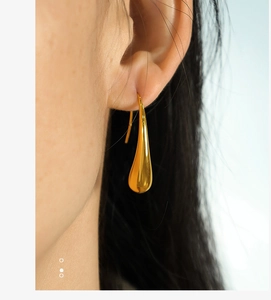 Close-up of elegant gold water drop earrings worn by a model with a polished finish