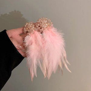 Close-up of pink feather earring with crystal clusters and elegant silver needle texture