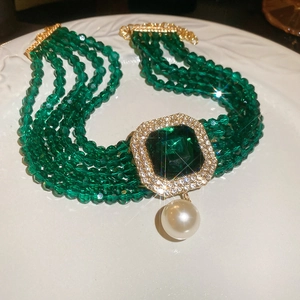 Macro view of luxury multi-layer green crystal bead necklace with emerald pendant in ceramic dish