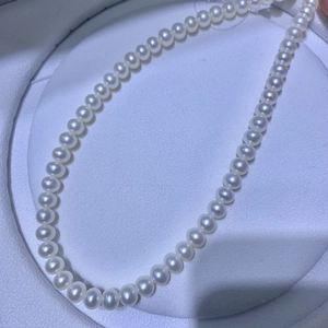 Elegant single strand white pearl necklace featuring high luster round beads on tray
