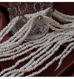 Vue macro de perles d'eau douce naturelles irrégulières de 3-4mm sur soie rouge