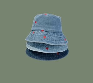 Detailed view of denim bucket hats in three blue shades with red heart embroidery