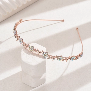 Detail shot of rose gold flower vine headband with sparkling crystals on white stand