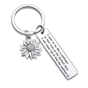 Close-up of engraved stainless steel bar and sunflower charm on a silver keychain