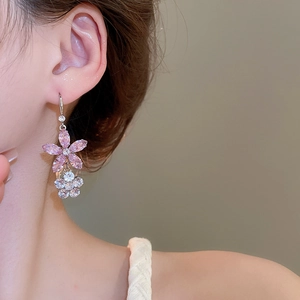 Gros plan d'élégantes boucles d'oreilles fleurs en zircon rose et blanc sur mannequin