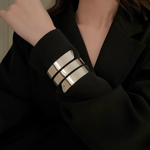 Dettaglio del bracciale a spirale in argento lucido sopra la manica di un blazer