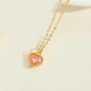Detailed macro view of orange-pink heart-shaped gemstone pendant on gold chain