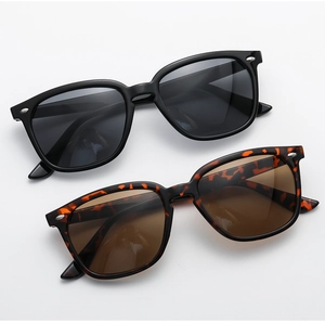 Close-up of classic square frame sunglasses featuring silver rivet details in black and tortoise