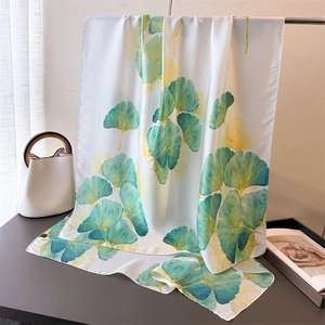 Détail d'une écharpe en soie avec motif de feuilles de ginkgo élégant vert et jaune