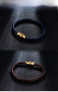 Detail view of woven leather bracelets in navy and brown with magnetic gold clasps