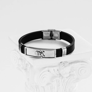 Men's black silicone bracelet with stainless steel skull plate on white stone pedestal
