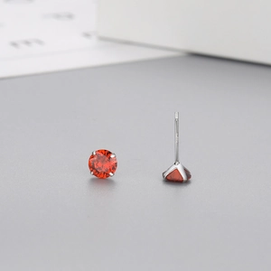 Detailed view of red round-cut zircon studs featuring classic silver four-prong settings