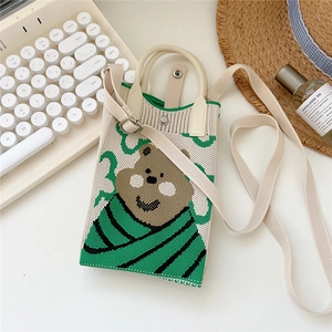 Detail of a beige knitted phone bag with green striped scarf bear pattern and strap