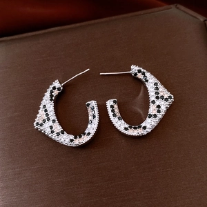 Macro detail of 18K gold plated C-shaped earrings with pavé zircon leopard pattern