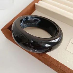 Minimalist marbled resin bangle bracelet with black and white ink pattern and polished finish
