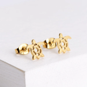 Golden sea turtle stud earrings in brushed stainless steel finish on a stone base