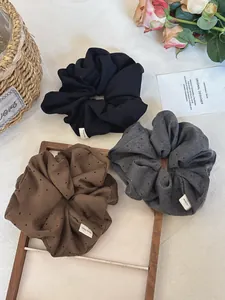 Detailed view of handmade polka dot hair scrunchies set in black, grey and brown colors