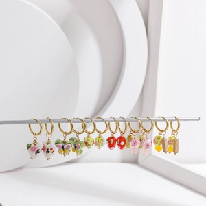 Detail of colorful hand-painted ceramic earrings with gold hoops and floral patterns
