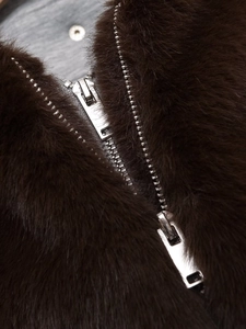 Detailansicht des Metallreißverschlusses an einer dunkelbraunen Webpelzjacke mit Kapuze