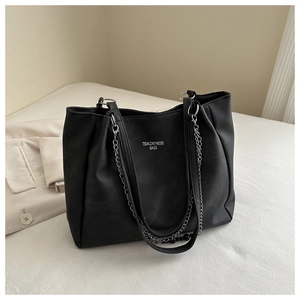 Detail of a black leather tote bag with silver chain straps and TIDALDRYNESS logo