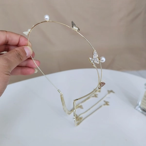 Close-up of golden headband featuring rhinestone butterflies, pearls and long tassel chains