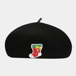 Close-up of a black wool beret featuring a detailed Christmas stocking embroidery