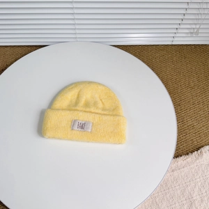 Detail of yellow knit beanie featuring fluffy texture and a square cloth label