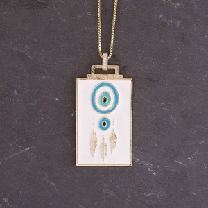 Detail of gold rectangle pendant with white enamel evil eye and three feather charms