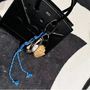 Nahaufnahme von Baseball-Anhänger mit Holzschläger und Lederhandschuh an Handtasche