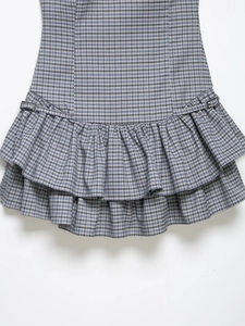 Detail of blue plaid dress featuring layered ruffle hem and silver metal side buckles