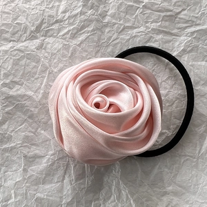 Detail of pink satin rose hair tie with elegant layered petals and elastic band