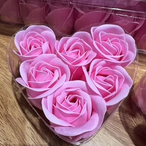 Detail of 6 pink scented soap roses arranged in a heart-shaped gift box on wood