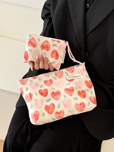 Detail of cute heart pattern fabric cosmetic bags and coin purse in model hands