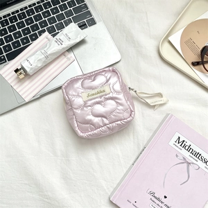 Pink heart quilted silk sanitary pouch shown on a desk with a laptop and accessories