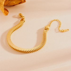 Détail d'un bracelet en acier inoxydable doré à mailles écailles sur fond beige