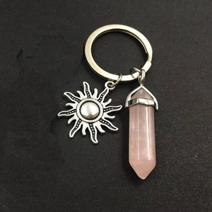 Detail of pink crystal hexagonal column with a sun-shaped pendant on silver keychain