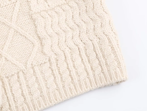 Makro-Detail von beige gestricktem Stoff mit Rautenmuster und Zopfstrick-Texturen