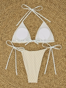Flat lay of white crochet lace bikini with pearl chains on a round straw beach mat